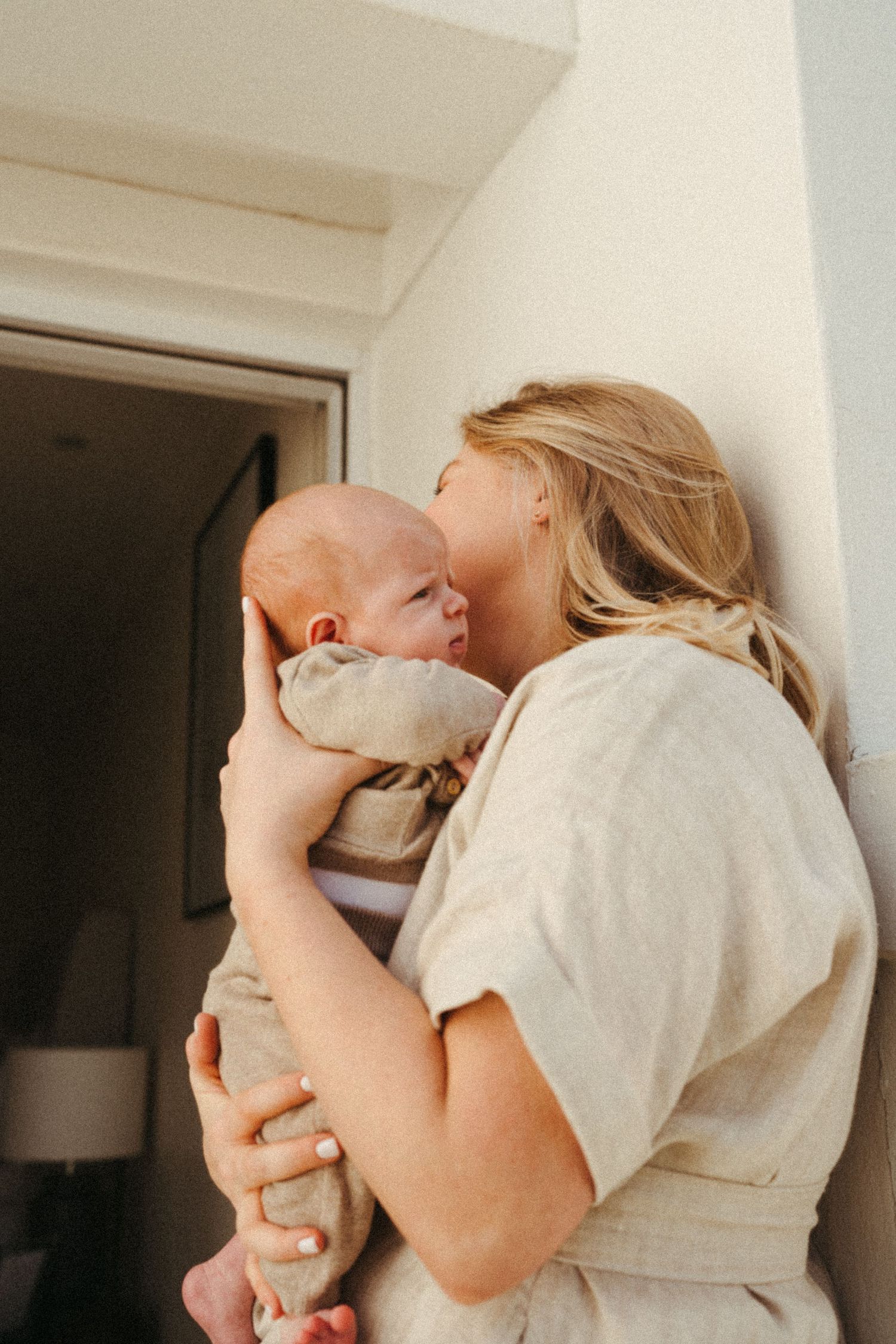 Tender moments between a couple wearing light colored clothing on a bright white balcony.