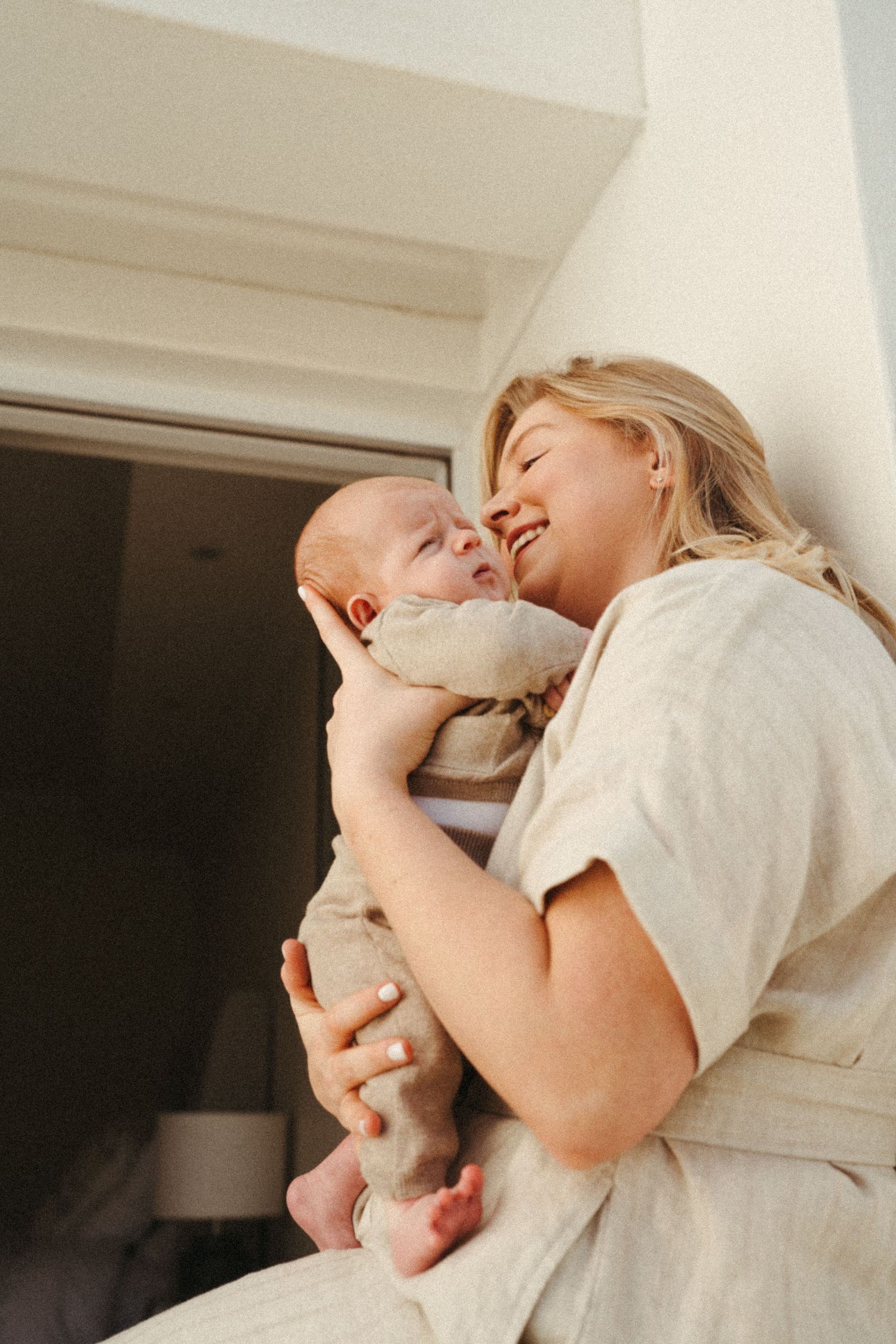 A tender moment between parent and newborn baby in soft white lighting.