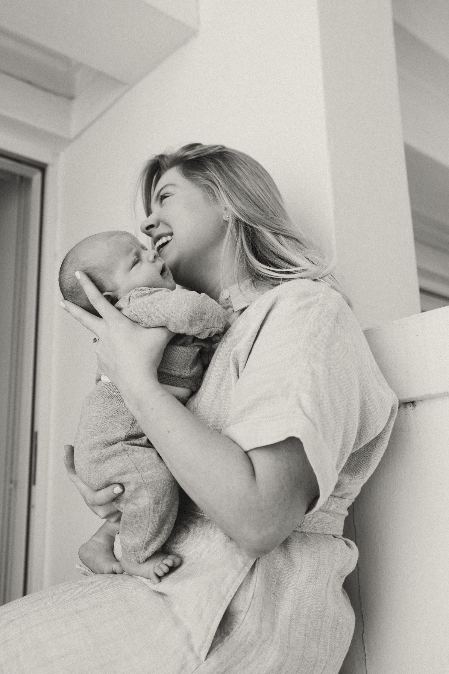 Joyful interaction between parent and infant against white walls.