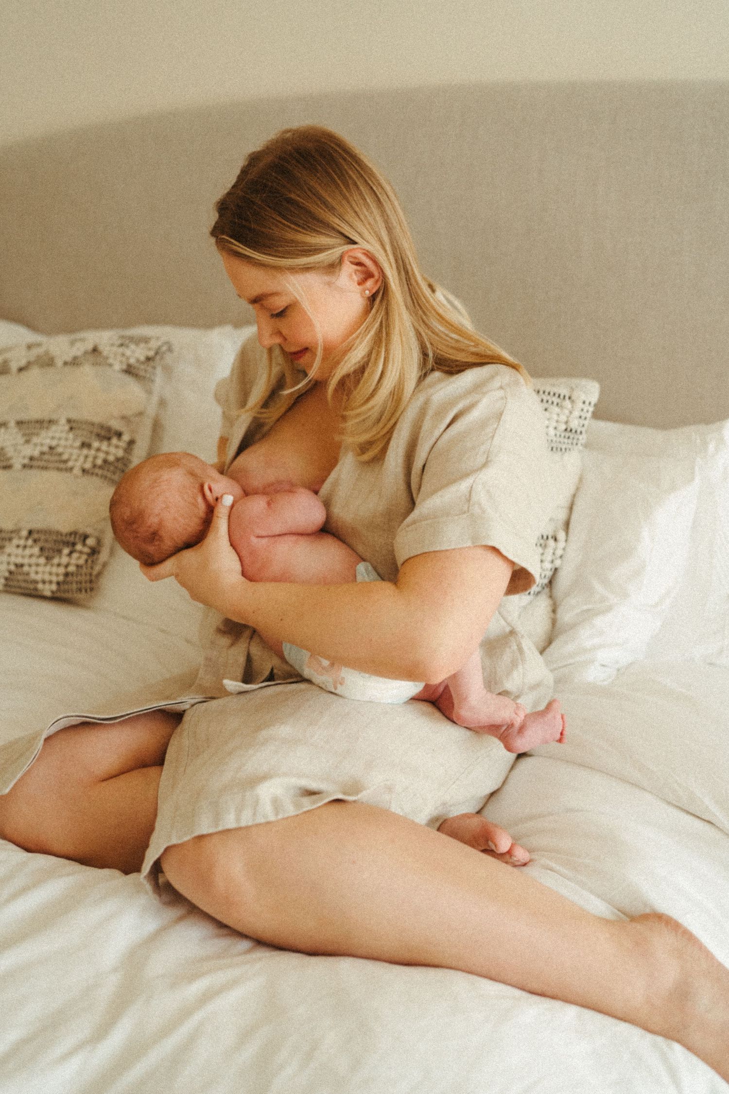 Peaceful moment between parent and baby on white bedding.