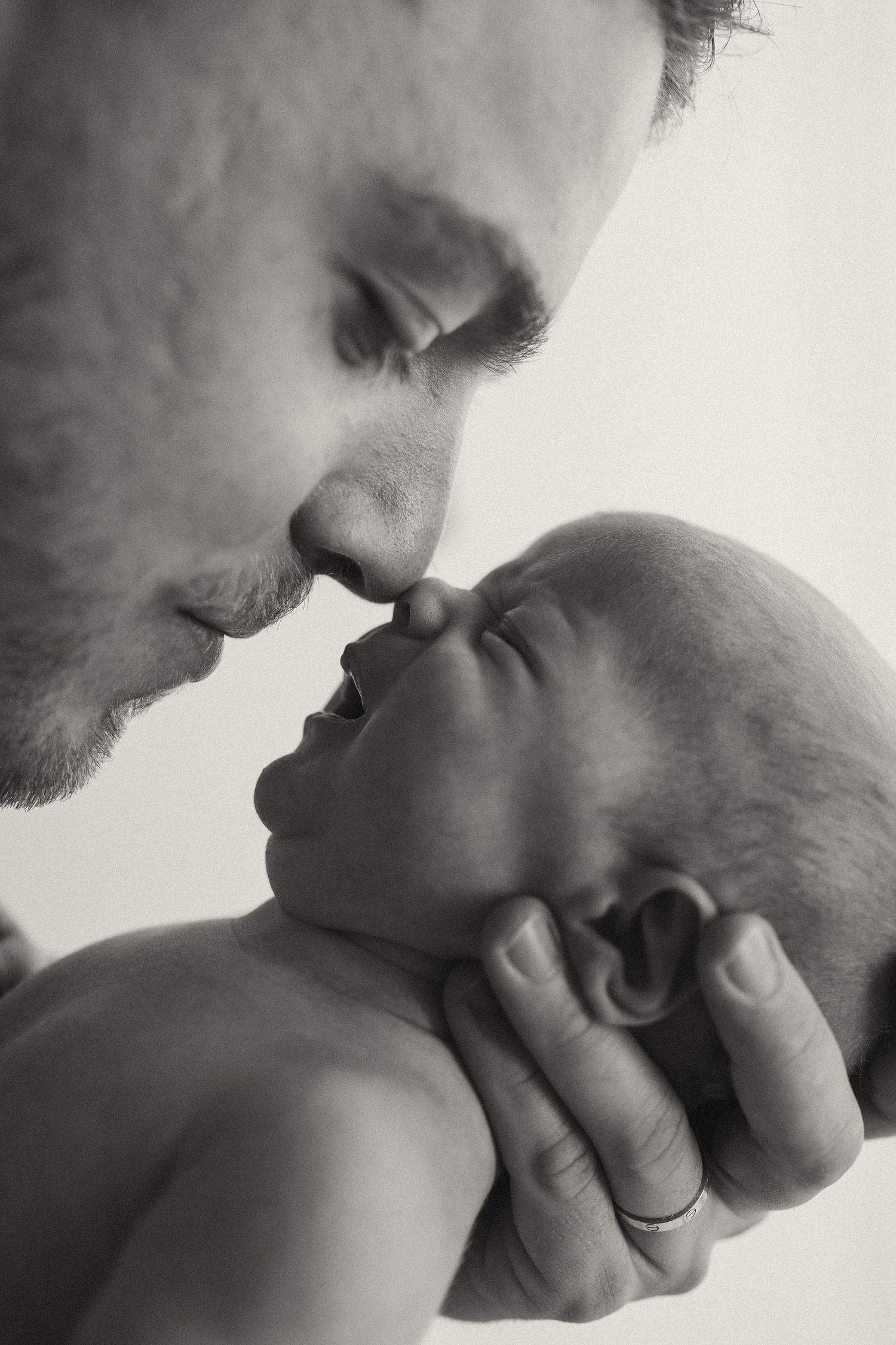 Close-up black and white photographs showing gentle interaction with a baby.