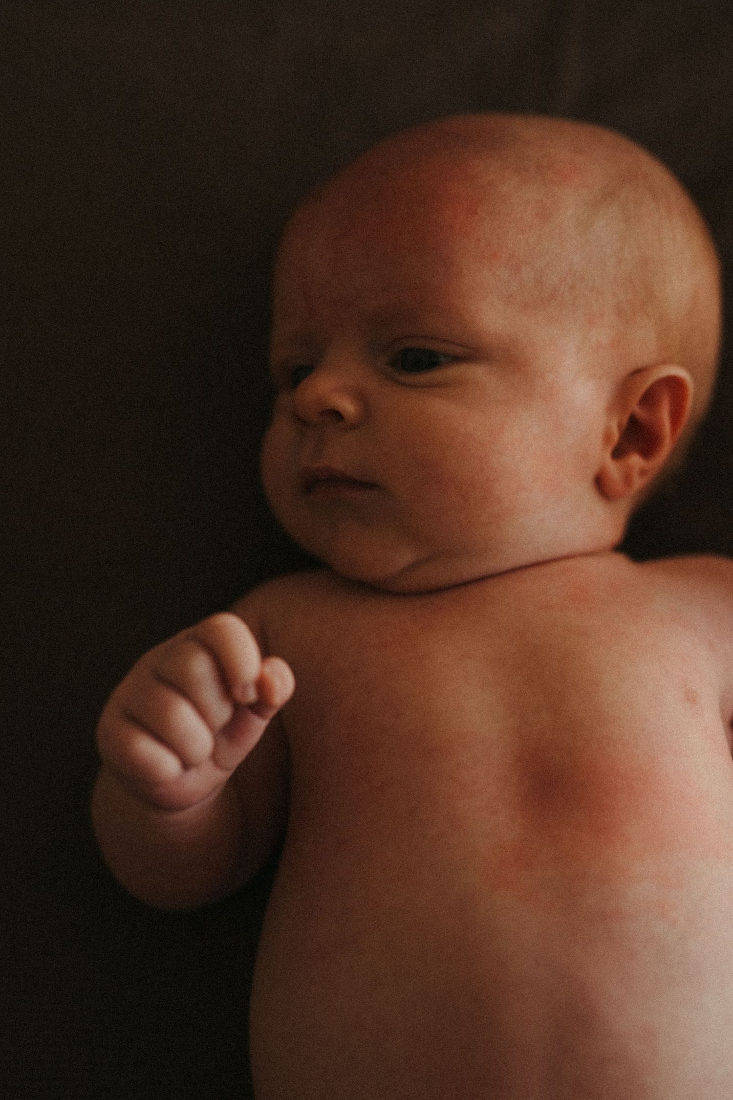 Artistic series of photographs showing a newborn baby in dramatic lighting.