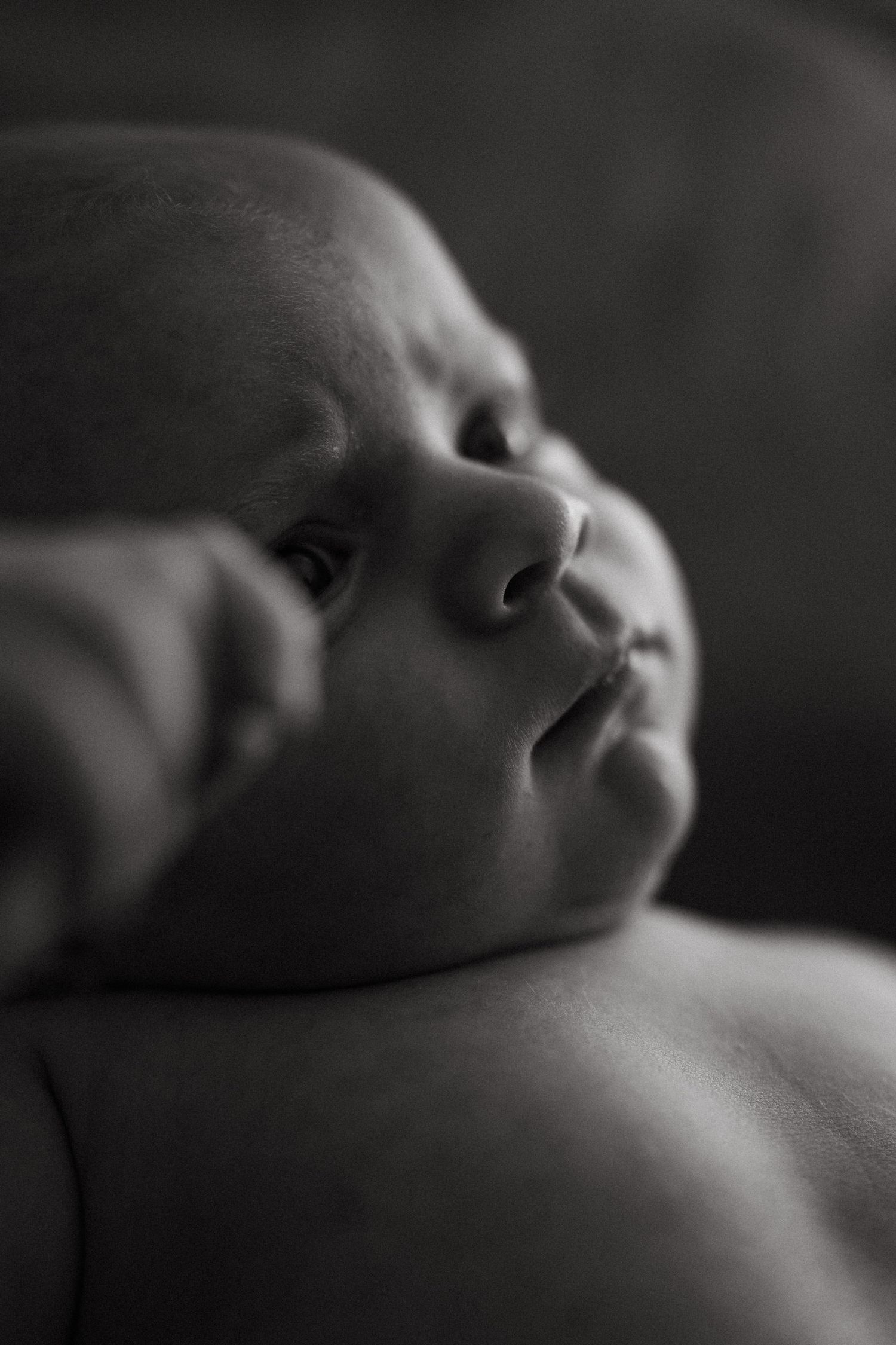 Side profile of a peaceful sleeping newborn in monochrome.