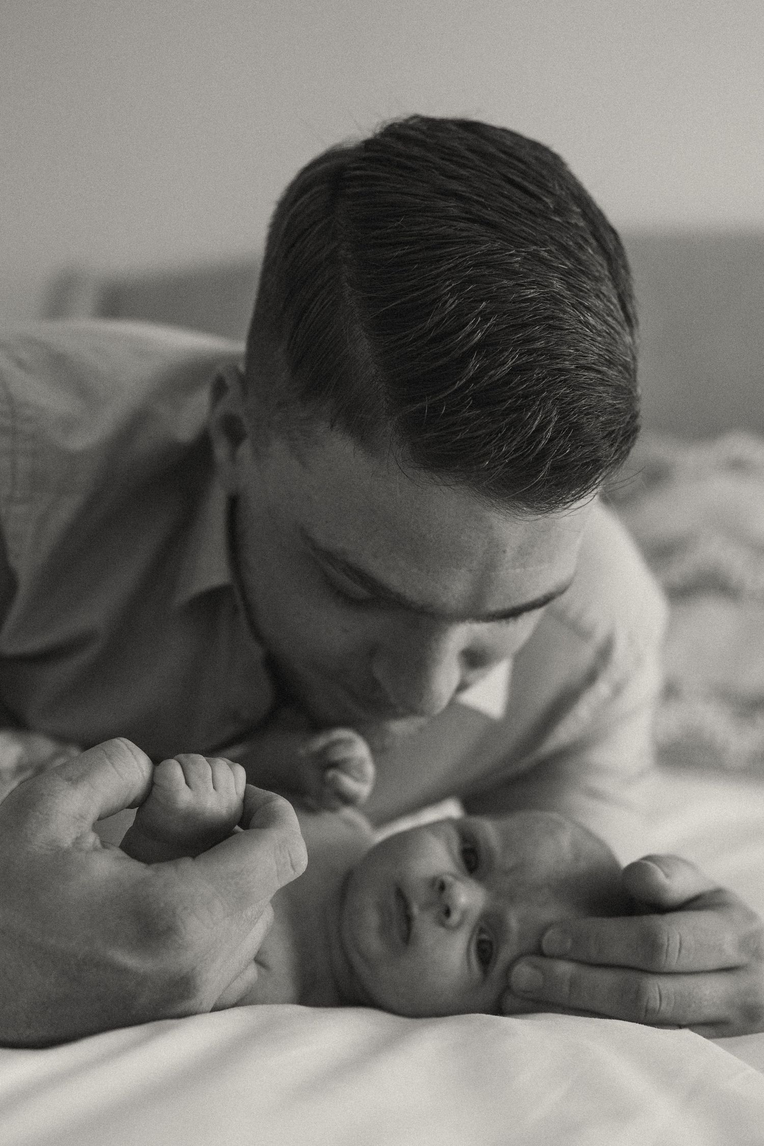 Intimate black and white photo of parent and baby sharing a tender moment on bed.