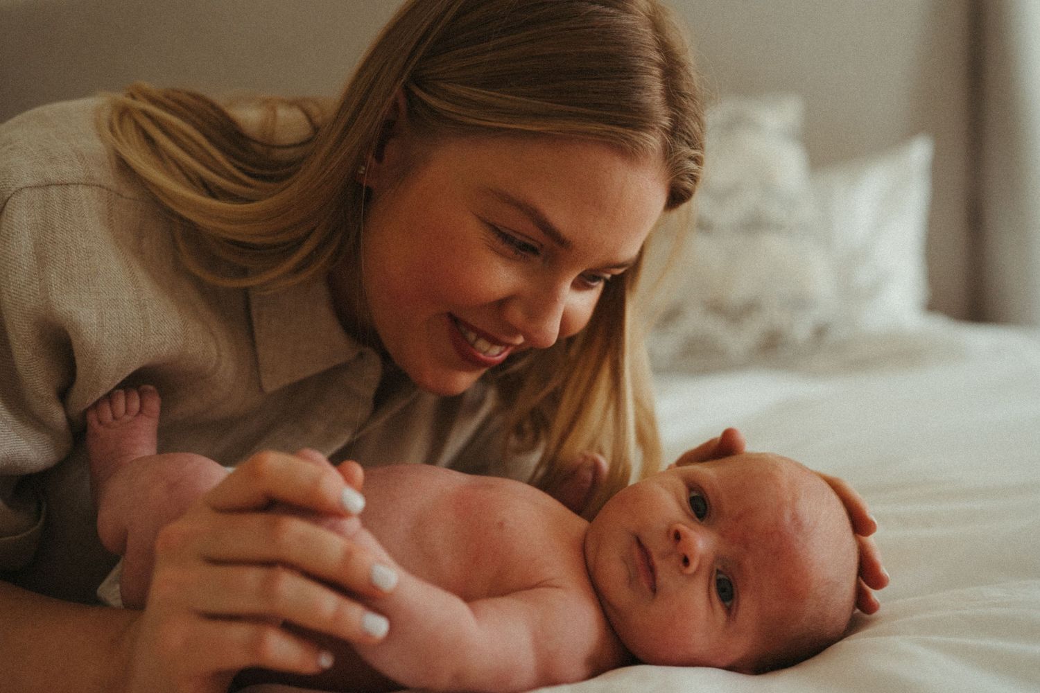 Parents lying on bed sharing intimate moment with their newborn baby.