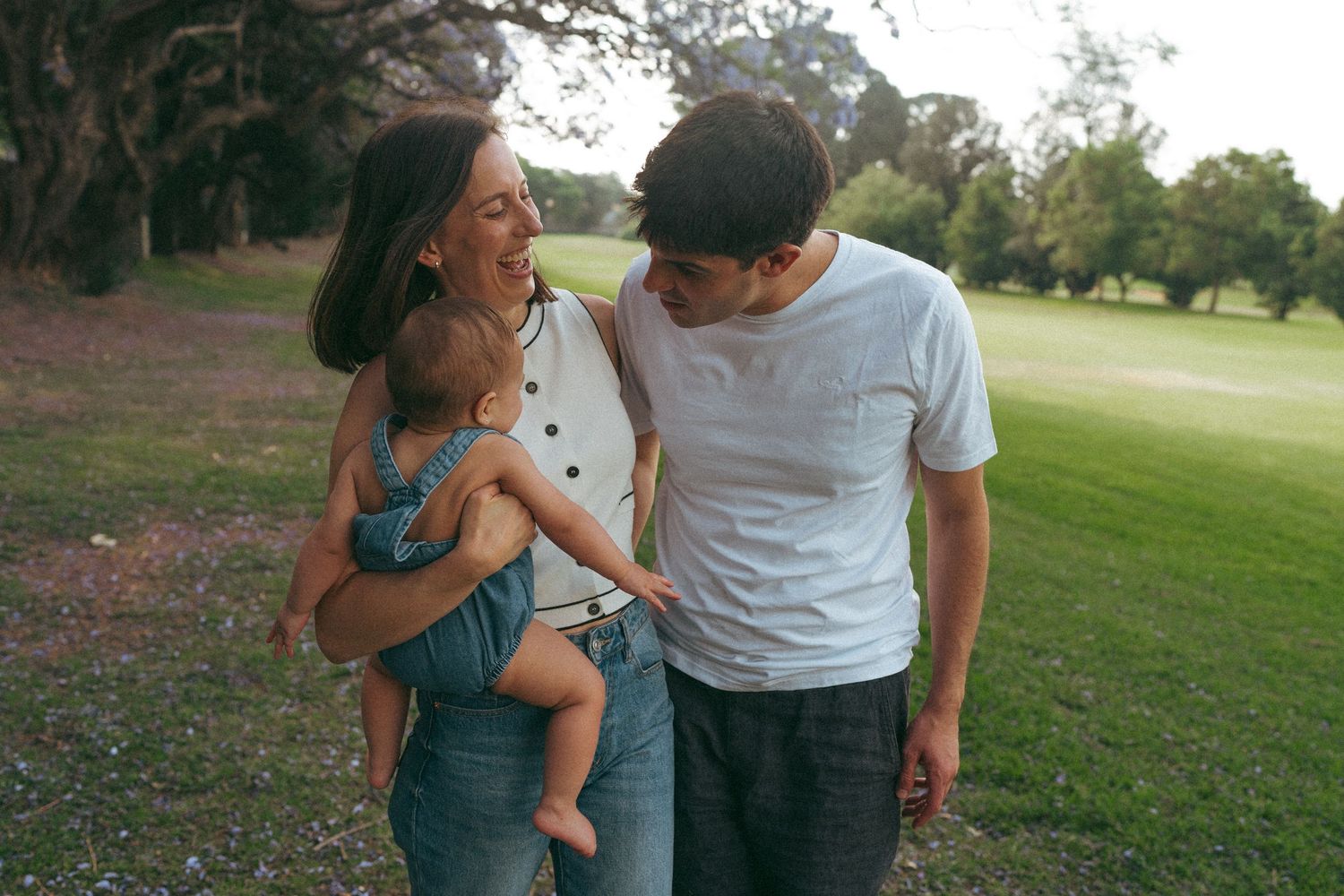 Family enjoying a casual outdoor photo session in a grassy park setting.