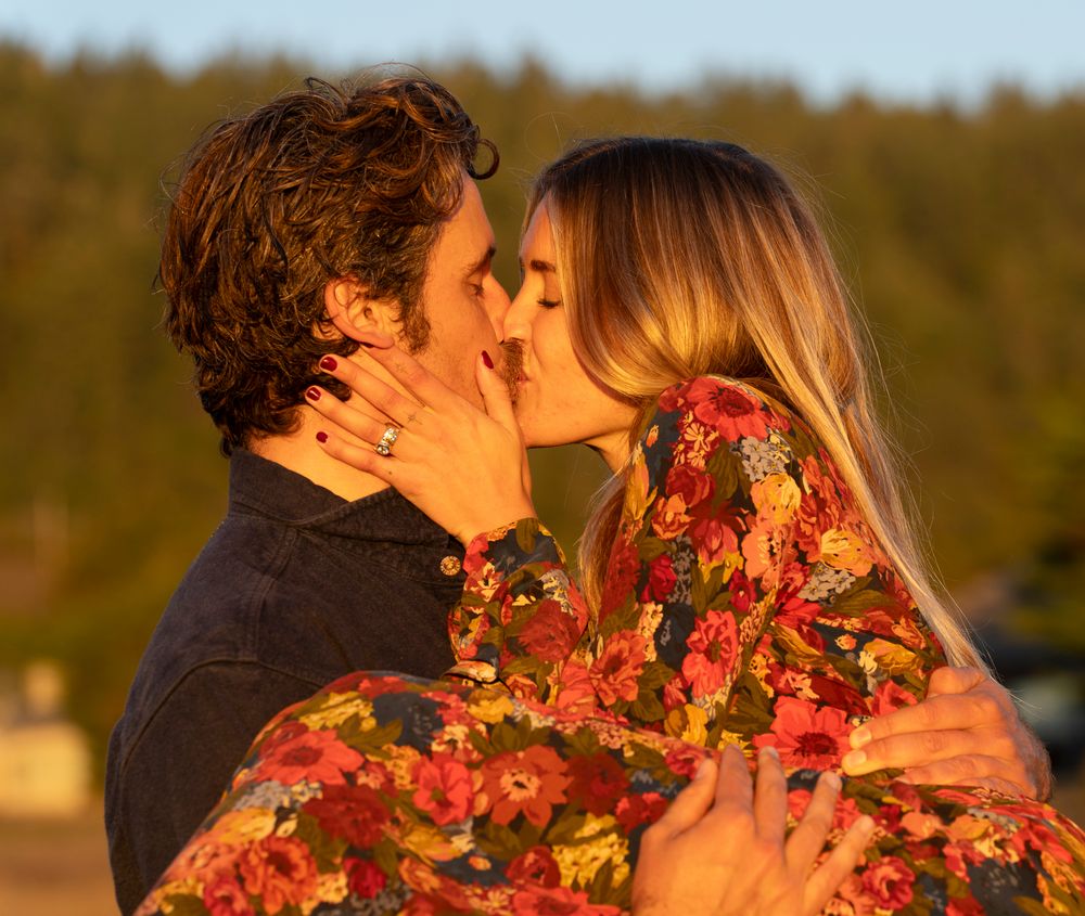 A couple in a floral dress sharing an intimate moment at golden hour.
