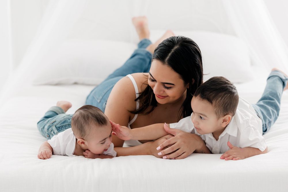 Family enjoying tender moments together while relaxing on white bedding in casual intimate setting.