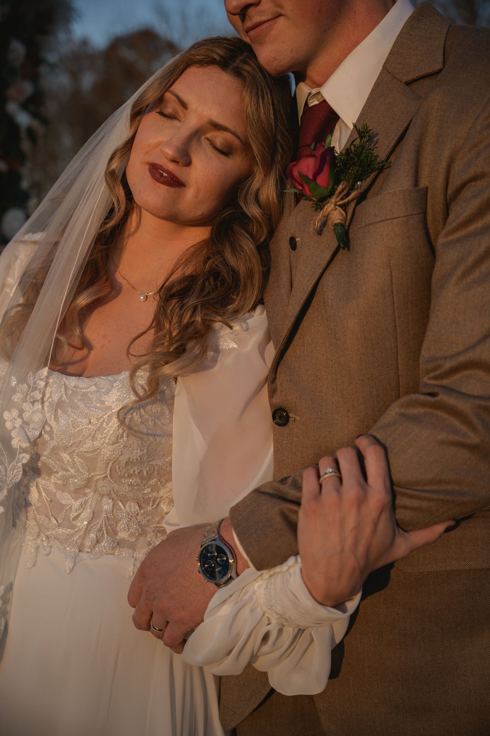 Intimate moment between newlyweds during golden hour with groom wearing brown suit.