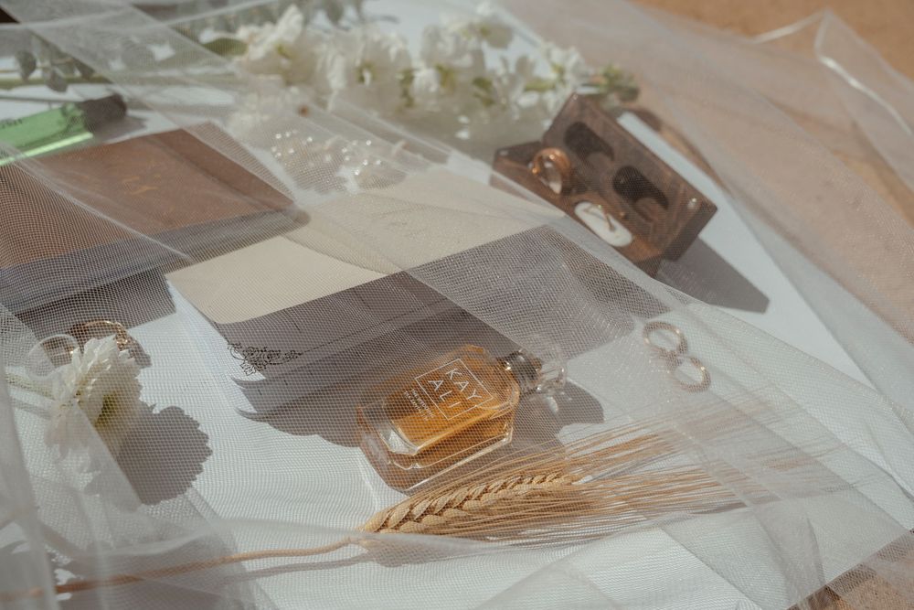 Wedding details including perfume bottles and delicate accessories arranged on a light surface.