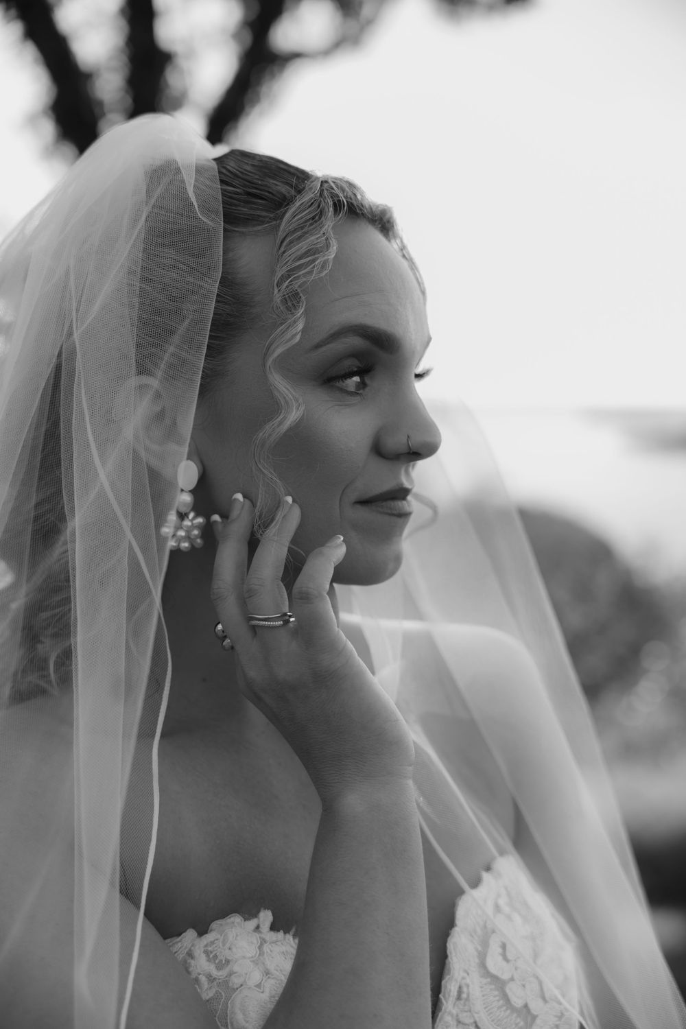 Black and white artistic portrait showing delicate bridal details and flowing veil.