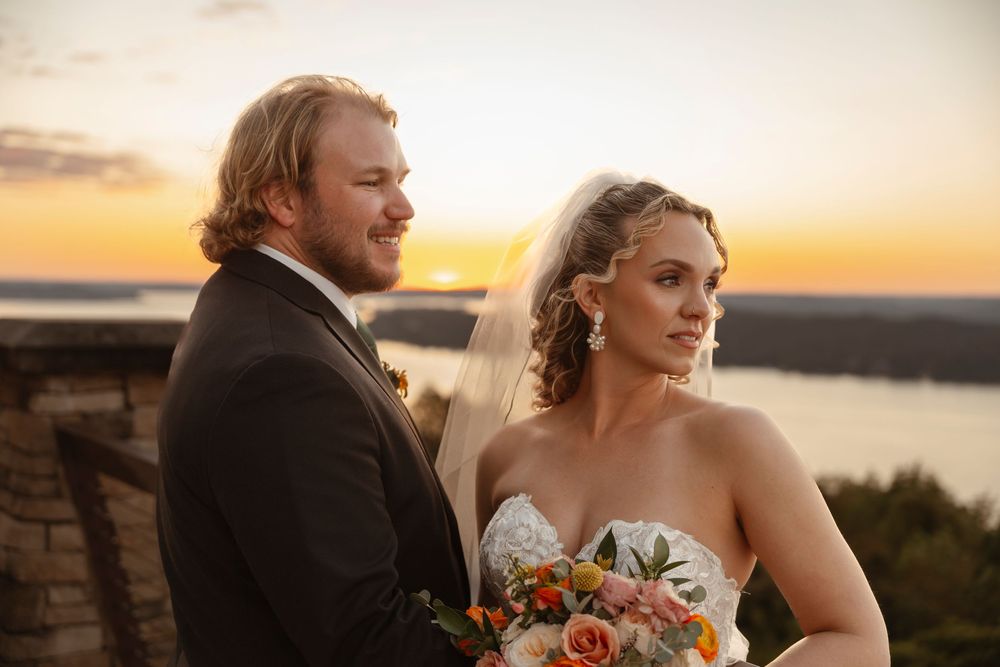 Newlyweds share tender moment at sunset overlooking coastal vista.