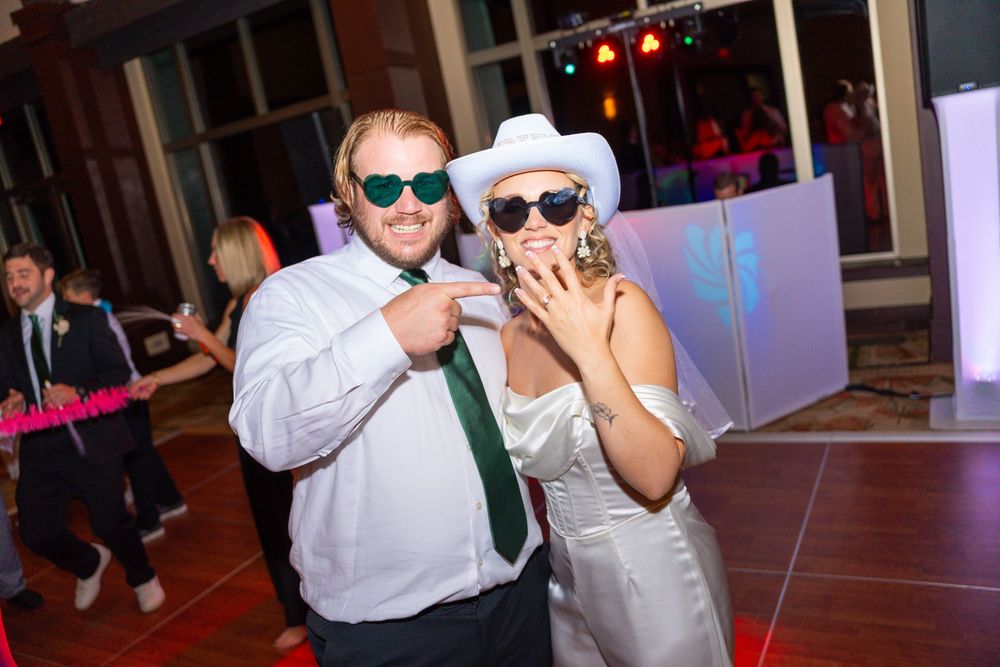 Wedding reception party guests dancing and celebrating with colorful lighting and sunglasses.