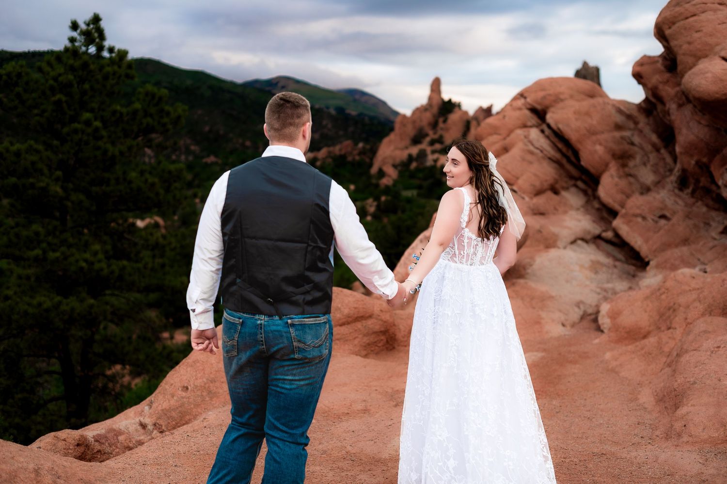 A couple takes wedding photos among dramatic red rock formations at Colorado's Garden of the Gods at sunset.
