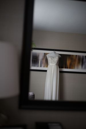 Reflection in the mirror of a white wedding dress handing on a framed abstract photo.