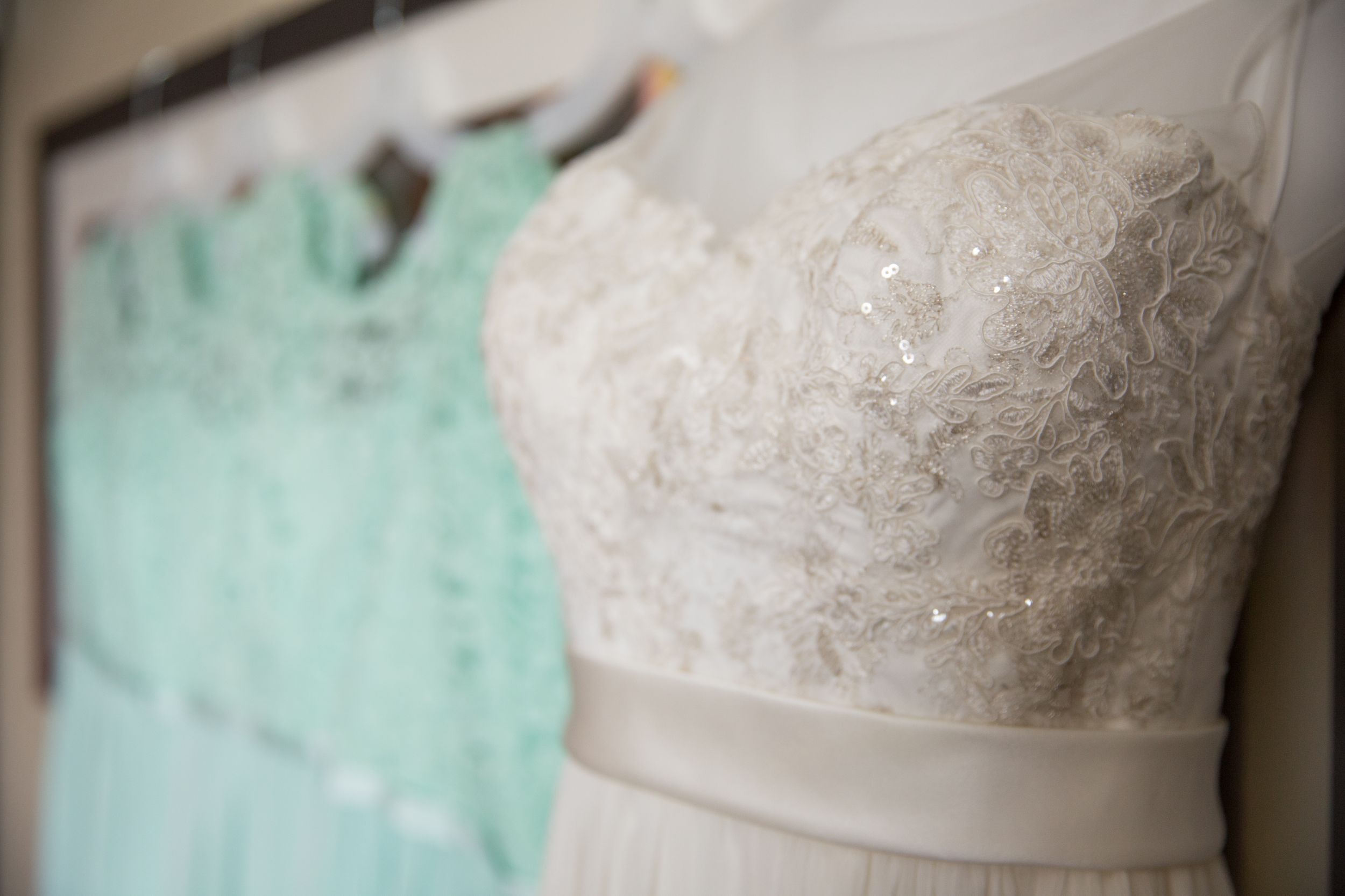 Wedding dress on a frames photo. Bridesmaids dresses hang in a row behind.