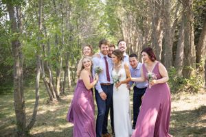 Bridal party surprises bride and groom surrounding them with a hug.