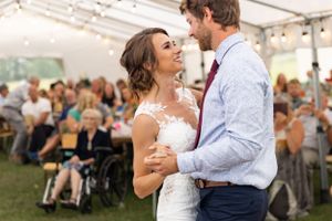 Bride and groom share their first dance. their guests sit watching in the backround.