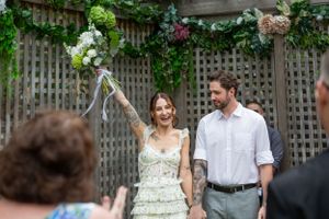 Bride throws her bouquet in the air to celebrate, her groom holds her hand as they walk back up the aisle.