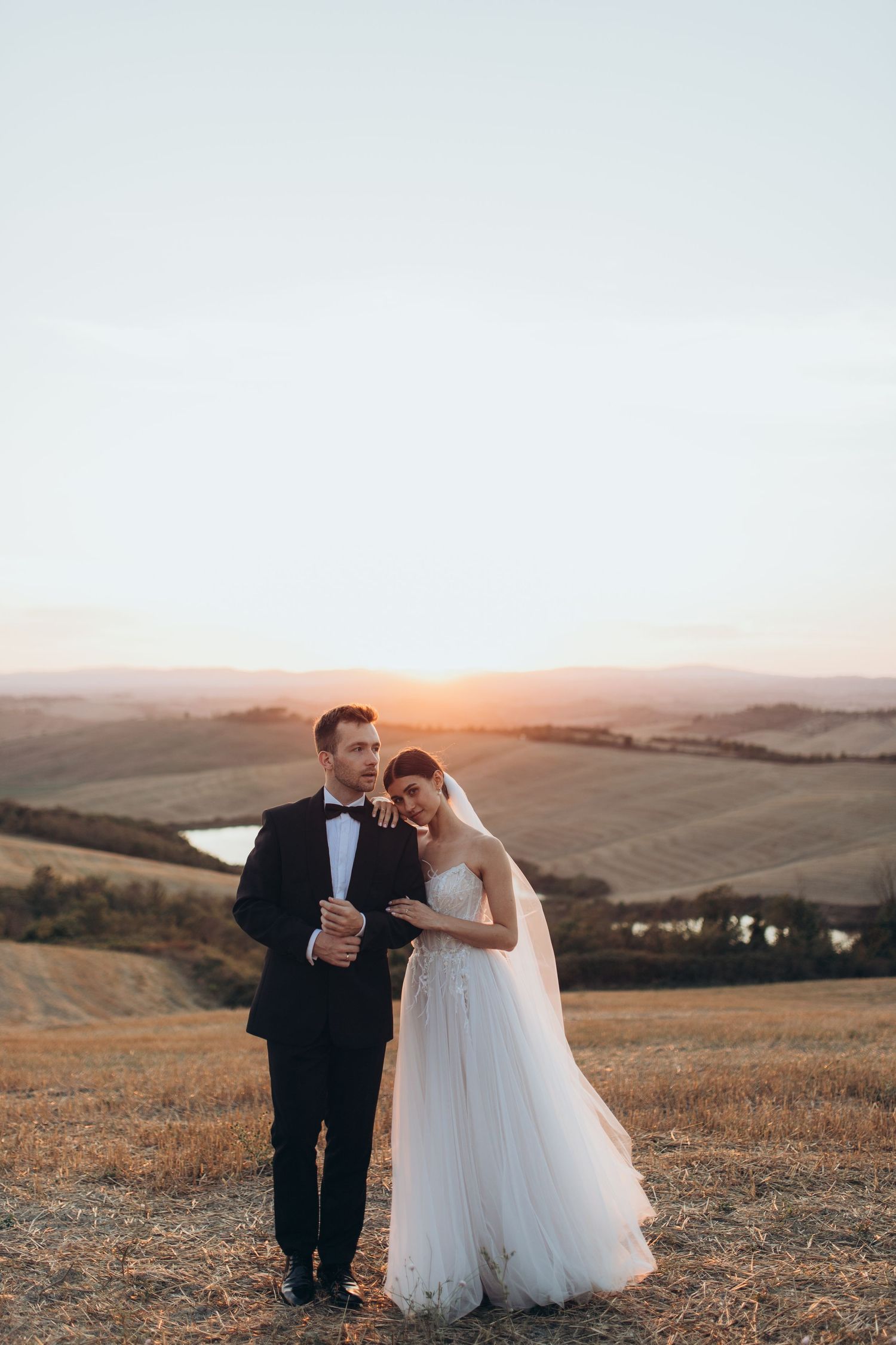 Romantic sunset wedding portrait in rolling golden hills with soft glowing light.