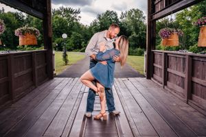 A couple in casual attire shares a romantic dance on a covered wooden deck.