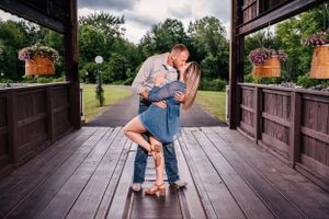 A couple shares an intimate moment on a wooden deck with hanging flower baskets.