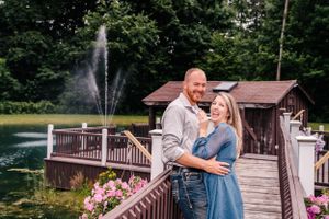 A loving embrace on a wooden deck with a fountain and small building in the background.