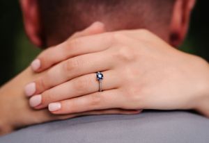 A close-up shot of an engagement ring with hands embracing.