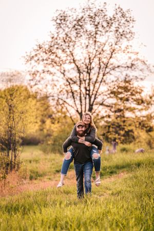A playful piggyback ride moment captured in a grassy field during golden hour.