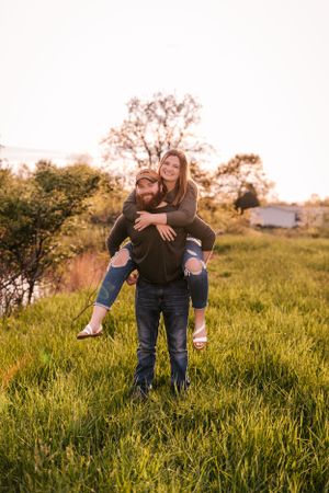 A playful piggyback ride in a sunlit grassy field during golden hour.