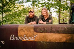 A couple leans on a vintage Brockway truck during an outdoor photoshoot.