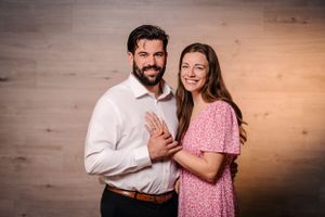 Couple in coordinated formal attire pose together against wooden wall backdrop.