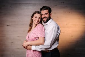 Happy couple in coordinated pink and white outfits pose for engagement photos.