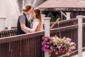 A romantic moment shared on a wooden bridge with pink floral decorations.