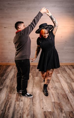 A couple dances together on wooden floors, with one person twirling the other.