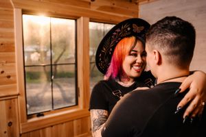 Intimate moment between couple in rustic cabin setting with window light.