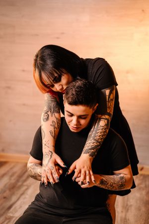 Intimate embrace with tattooed arms wrapped around in tender moment.
