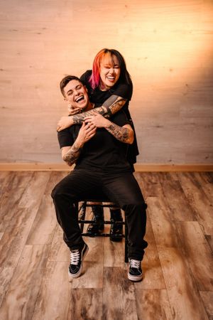 Candid moment of laughter while sitting on wooden stool in rustic setting.
