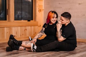 Casual couple sitting on wooden floor sharing intimate moment in cabin setting.