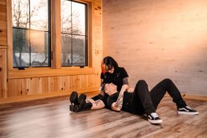 Relaxed couple lounging on wooden floor near window in rustic cabin.