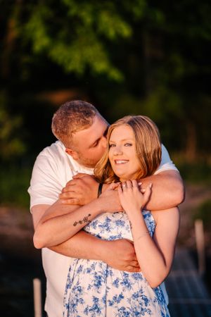 Romantic embrace captured in warm evening light with natural green backdrop.