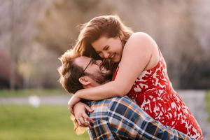 An intimate embrace between a couple in coordinating outfits during an outdoor photo session.