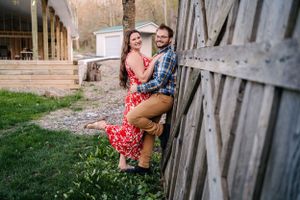 A romantic countryside photo shoot with a couple in coordinating red dress and plaid shirt outfits.