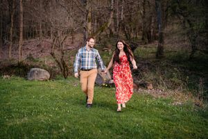 A couple walks through a grassy field wearing complementary outfits of red and plaid.