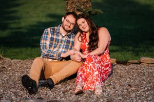 A tender moment captured between a couple sitting on gravel in coordinated casual outfits.