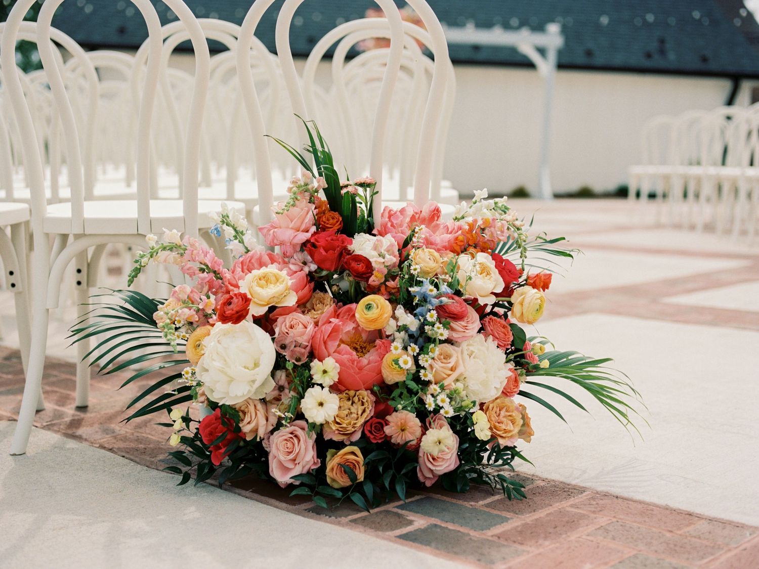 Vibrant colorful floral arrangement of pink, red, and yellow roses at wedding ceremony.