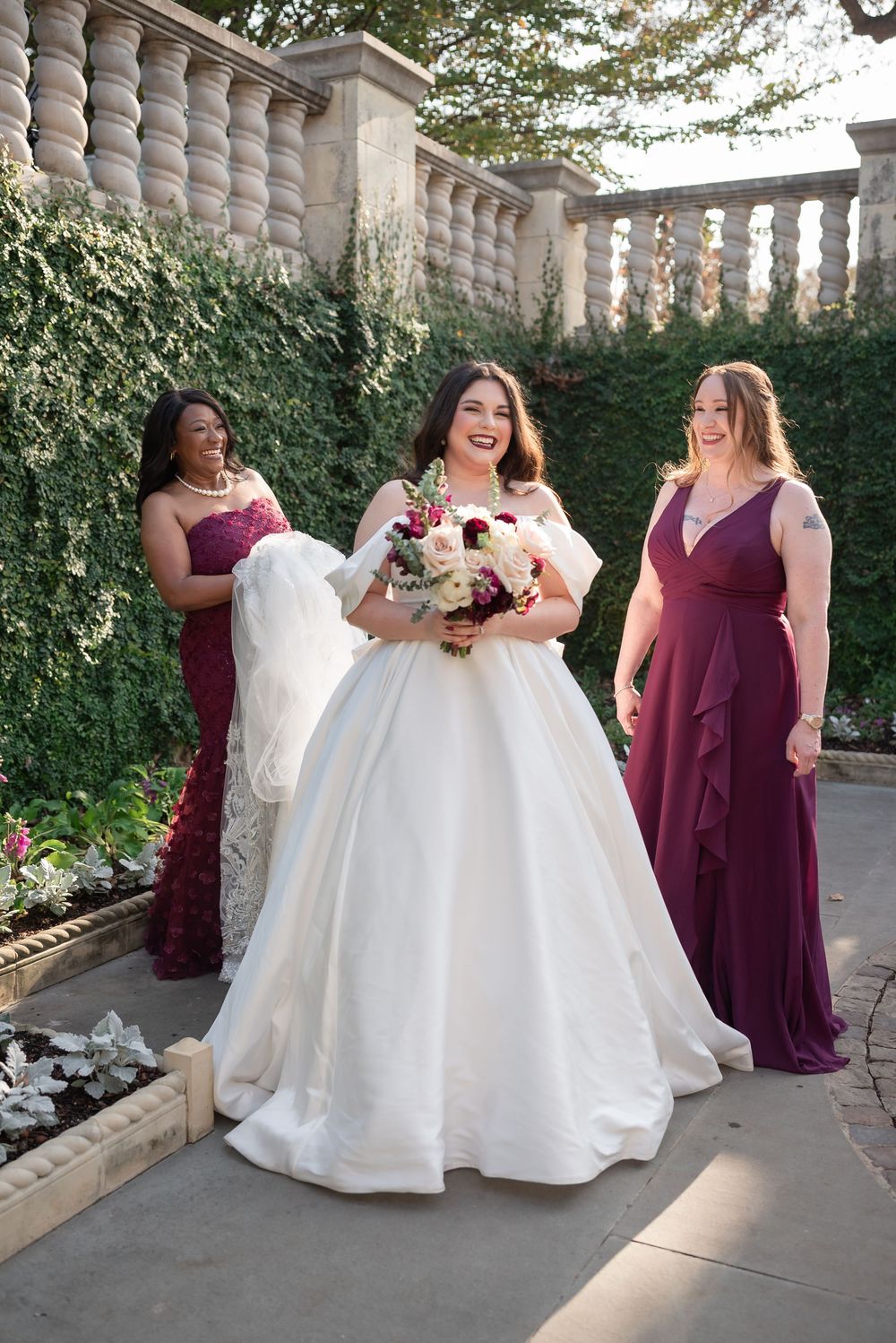 Bride with bridesmaids in burgundy dresses at garden wedding in Dallas Texas