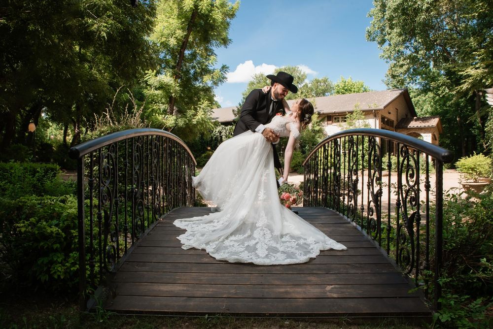 Bride and groom dip kiss on garden bridge at the springs weddings & events venue during romantic portrait