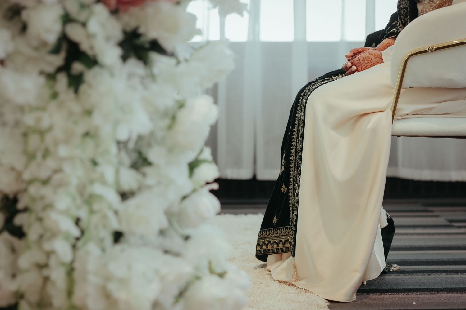 Elegant white floral arrangements frame traditional wedding attire details in an indoor setting.