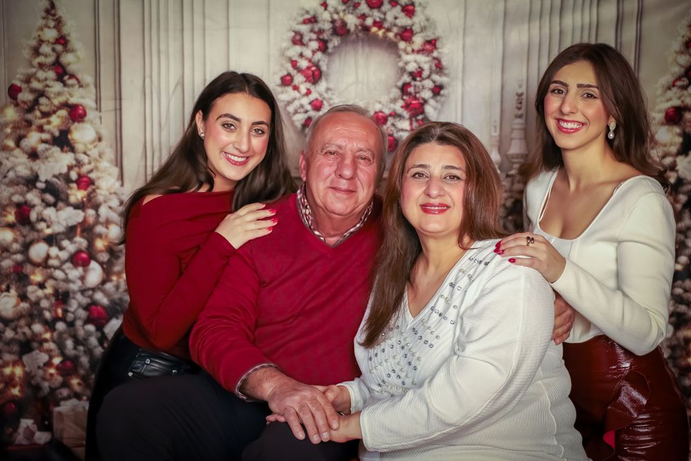 Holiday family portraits in front of a decorated Christmas tree with white and red decor.